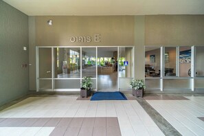 A hotel entrance with a tiled floor, a blue carpet, and potted plants. - Sea View 22 at Lumpini Jomtien (Pattaya)