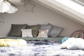 A cozy attic bedroom with a sloped ceiling, a bed with grey bedding and patterned pillows, and a star-shaped decoration. - resin passion || Braunlage (Braunlage)