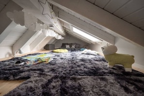 Un espace de jeux pour enfants avec un tapis moelleux, des jouets et un luminaire en forme d’étoile.