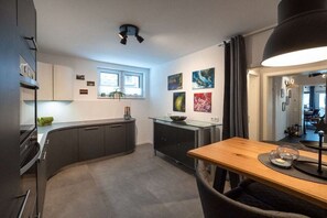 A modern kitchen with a curved countertop, a dining table with chairs, and artwork on the walls. - resin passion || Braunlage (Braunlage)