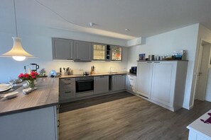 A modern kitchen with grey cabinets, a wooden countertop, and a built-in oven. - Holiday apartment in Damp with swimming pool (Damp)