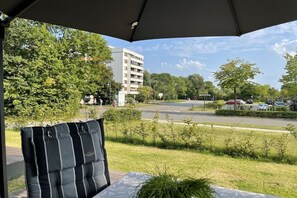 A covered outdoor seating area with a view of a road and buildings. - Holiday apartment in Damp with swimming pool (Damp)
