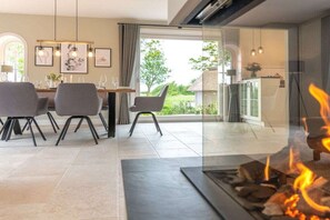 Un comedor moderno con chimenea, una mesa de comedor con sillas y vistas al exterior.