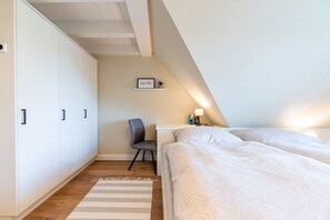 A bedroom with a bed, a chair, a desk, and a wardrobe.
