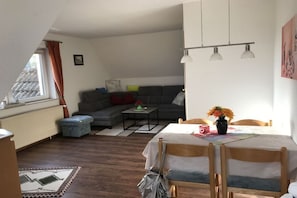 A living room with a sofa, a dining table with chairs, a coffee table, and a window with curtains. - Holiday apartment in Boren with swimming pool (Boren)