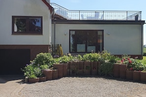 A building with a balcony, a window, and a gravel area with raised flower beds. - Holiday apartment in Boren with swimming pool (Boren)