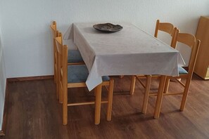 A dining table with a white tablecloth, surrounded by wooden chairs with blue cushions. - Holiday apartment in Boren with swimming pool (Boren)