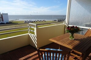 Ein Balkon mit Blick auf das Meer, einem Holztisch und einem Stuhl.