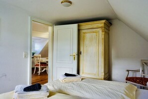 A bedroom with a bed, a wardrobe, and a door leading to another room. - Holiday apartment with 2 bedrooms (Wenningstedt-Braderup)
