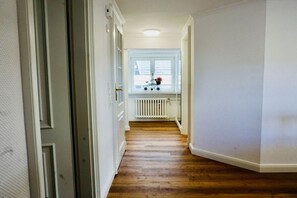 A hallway with wooden flooring, white walls, and a window with a bicycle decoration. - Holiday apartment with 2 bedrooms (Wenningstedt-Braderup)