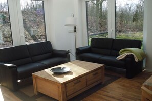 A modern living room with two black sofas, a wooden coffee table, and a floor lamp. - Holiday home in Kalkar with swimming pool (Kalkar)