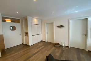 A modern interior with a wooden floor, white walls, and built-in cabinetry. - Villa Rossini - No. 4 (Norderney)