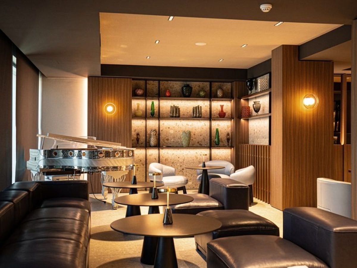 Un'elegante area lounge con divani in pelle, tavoli rotondi e un pianoforte a coda.