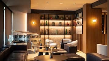 Un'elegante area lounge con divani in pelle, tavoli rotondi e un pianoforte a coda.