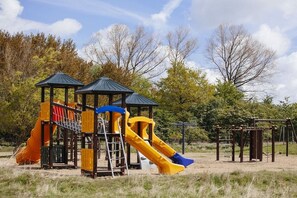 A playground with a slide and climbing structures. - "P-Liner" house type E plus (Neustadt\/Holstein - OT Pelzerhaken)
