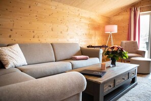 A cozy living room with a sofa, a coffee table, and a lamp. - "P-Liner" house type E plus (Neustadt\/Holstein - OT Pelzerhaken)