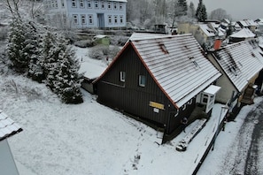 A snow-covered residential area with a large two-story house and a smaller adjacent building. - Holiday home with 4 bedrooms (Sankt Andreasberg)