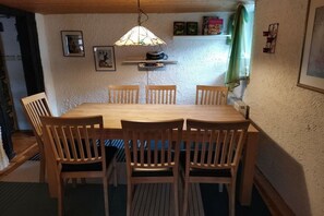 A dining area with a wooden table and chairs, a hanging light fixture, and framed pictures on the wall. - Holiday home with 4 bedrooms (Sankt Andreasberg)