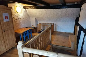 A room with a wooden staircase, a small table with blue chairs, and a crib. - Holiday home with 4 bedrooms (Sankt Andreasberg)