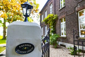 A building with a brick facade, a black metal gate, and a sign that reads 'KREBBER KLEINE GÖTTIN.' - Manor House Kleine Gönn (Xanten)