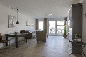Een moderne woonkamer met een bank, een eettafel en stoelen, een balkon met uitzicht, en een grote kast.