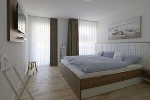 A bedroom with a bed, a television, a window with curtains, and a painting on the wall. - Holiday apartment with 1 bedroom (Cuxhaven)