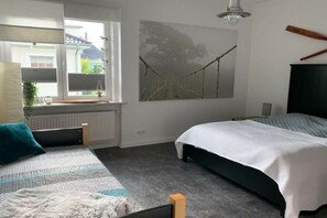 Un dormitorio con dos camas, una ventana con vistas, un cuadro en la pared y un radiador.
