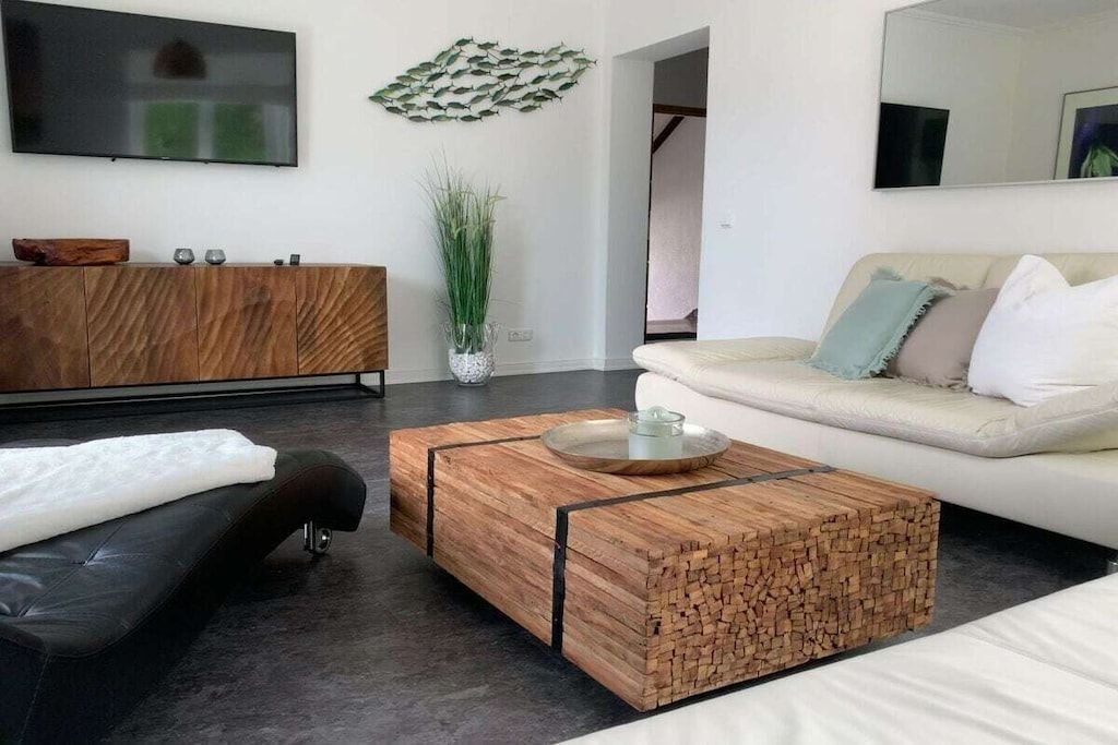 A modern living room with a wooden coffee table, a sofa, a TV, and a decorative wall piece.