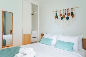 Une chambre d’hôtel avec un lit, une armoire, un miroir et une décoration murale en macramé.