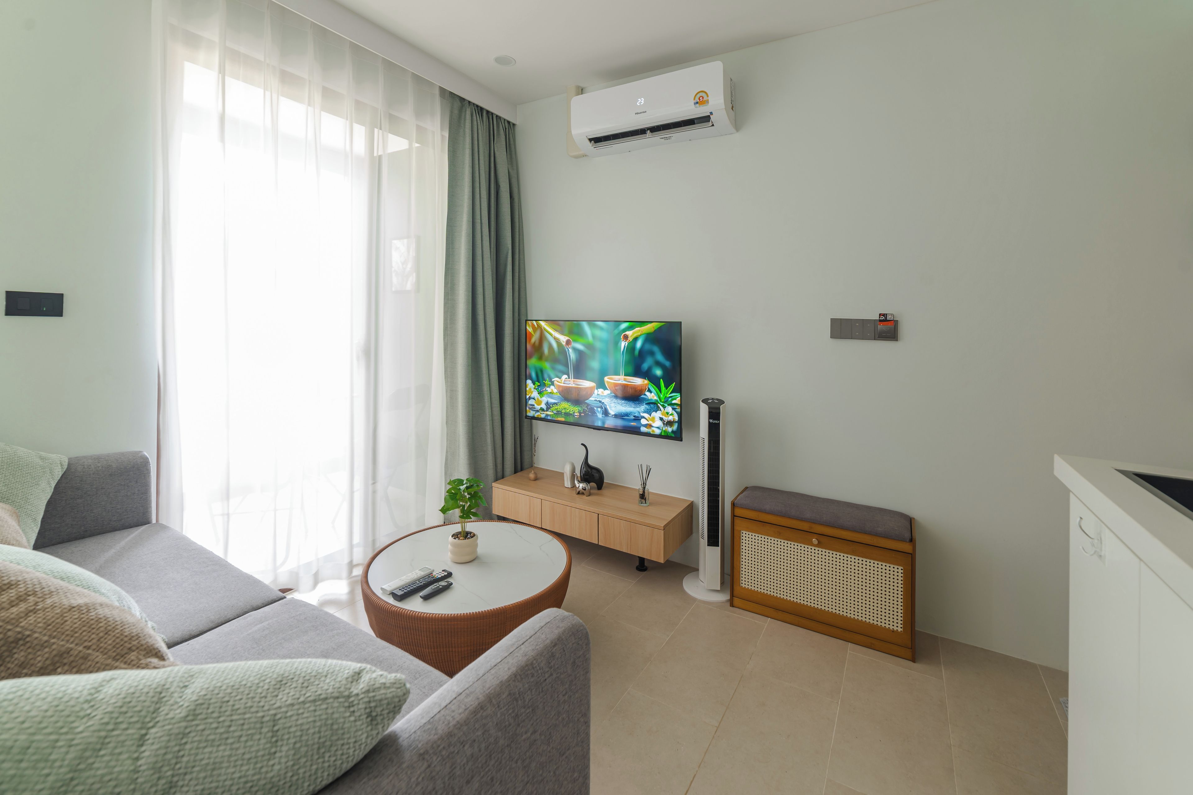 A modern living room with a sofa, a coffee table with a plant, a TV on the wall, and a radiator.
