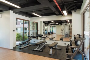 Une salle de sport équipée de matériel d’exercice, de miroirs et offrant une vue sur l’extérieur.