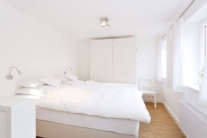 A minimalist bedroom with a bed, bedside table, and a wardrobe. - "Sun Garden" in the little house on the Rhine (Rees)