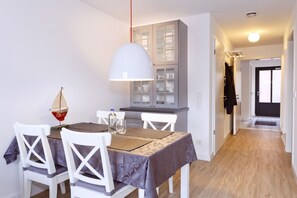 A dining area with a table set for four, a cabinet with glass doors, and a hallway leading to another room. - "Sun Garden" in the little house on the Rhine (Rees)