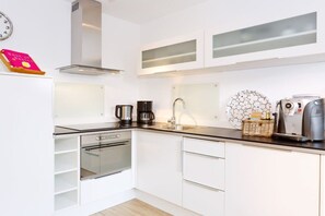 A modern kitchen with white cabinetry, a stainless steel range hood, a coffee maker, and a toaster. - "Sun Garden" in the little house on the Rhine (Rees)