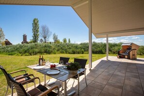 An outdoor patio with a table set for dining, chairs, and a grill. - "Shipping House" Type G plus (Neustadt\/Holstein - OT Pelzerhaken)