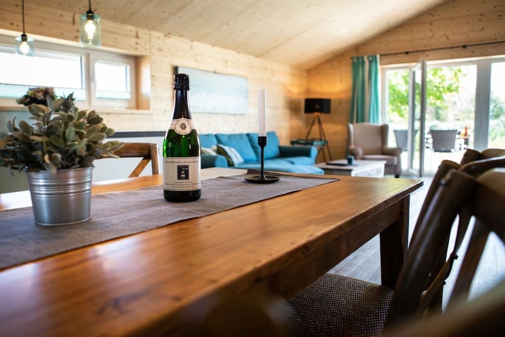 A wooden dining table with a bottle of wine and a candle.