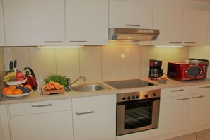 A kitchen with white cabinets, a stainless steel sink, a coffee maker, and a microwave. - Holiday apartment with 1 bedroom (Hasselberg)