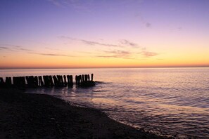 A beach scene with a wooden pier extending into calm waters during sunset. - Beach house "Admiral" (Neustadt OT Bliesdorf-Strand)