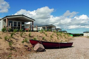 A coastal property with multiple beach houses, a gravel driveway, and a red boat. - Beach house "Admiral" (Neustadt OT Bliesdorf-Strand)