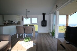 A modern living space with a kitchen, dining area, and a large window offering a view. - Beach house "Admiral" (Neustadt OT Bliesdorf-Strand)