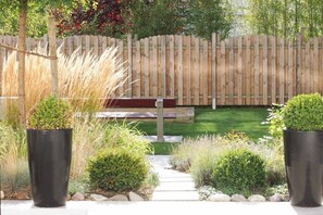 Ein Garten mit Holzzaun, einer Bank und Kübelpflanzen.
