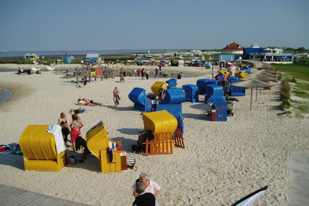 A beach with beach huts, a wooden deck, and a clear sky.
