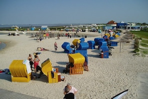 Ein Strand mit Strandkörben, einer Holzterrasse und einem klaren Himmel.
