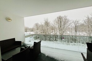 Ein Balkon mit Blick auf eine schneebedeckte Landschaft und kahle Bäume.