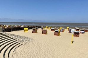 Ein Strand mit Reihen aus Holzstrandkörben und einem klaren Himmel.