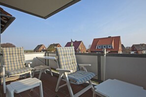 Eine Terrasse mit zwei Stühlen und einem Tisch, mit Blick auf ein Wohngebiet mit Häusern.