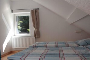 A bedroom with a window, a radiator, and a bed with striped bedding. - in the forester's lodge on the Brocken mountain - 2 bedrooms (Ilsenburg)
