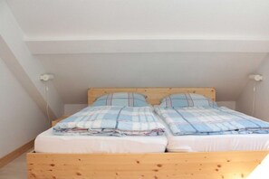 Ein Einzelbett aus Holz mit Kopfstütze, zwei Kissen und einer Decke.