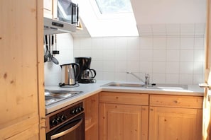 Eine kompakte Küche mit Backofen, Mikrowelle und Kaffeemaschine.