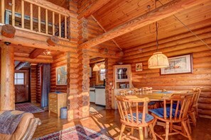 A log cabin interior with a dining area, wooden furniture, and a staircase. - Holiday home with 2 bedrooms (Butjadingen)